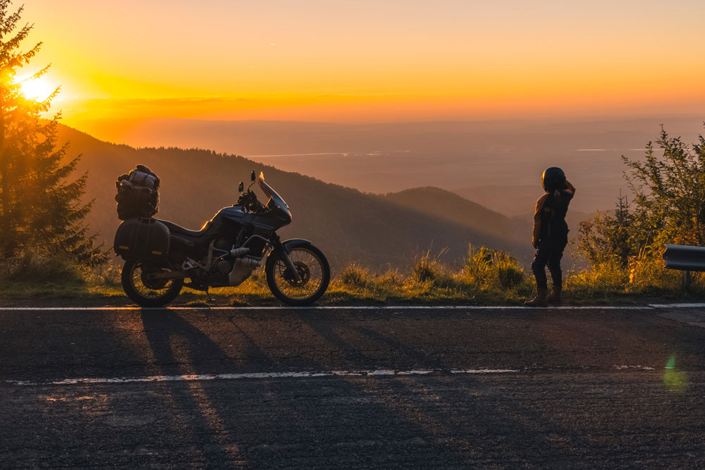 Biker stopped on roadside looking at sunset