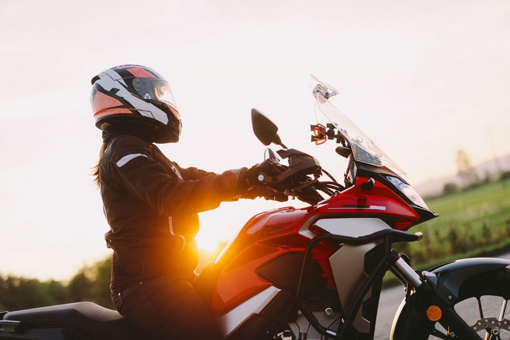 Woman riding motorcycle at sunset