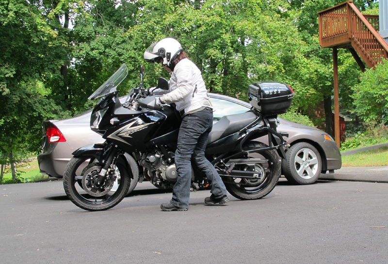 If both your feet can’t touch the ground when seated on a motorcycle and you need to back out of (or into) a parking spot, walk the motorcycle by standing next to it. Grasp both grips from the left side of the bike as you upright it from its sidestand. Use your body as leverage and lean the motorcycle against your right hip, while backing it up in neutral or with the clutch squeezed. Cover the front brake while moving slowly. Again, practicing this maneuver on a small bike first is ideal, so you know how to do it with a bigger bike.