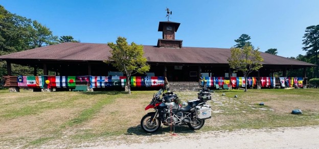 Picture09 Ruth’s flag adorned BMW R 1200 GS stands proudly in front of the dining hall which is also adorned with the country flags of each WIMA chapter at the rally. This photo symbolizes the unity and connection we share as women riders.